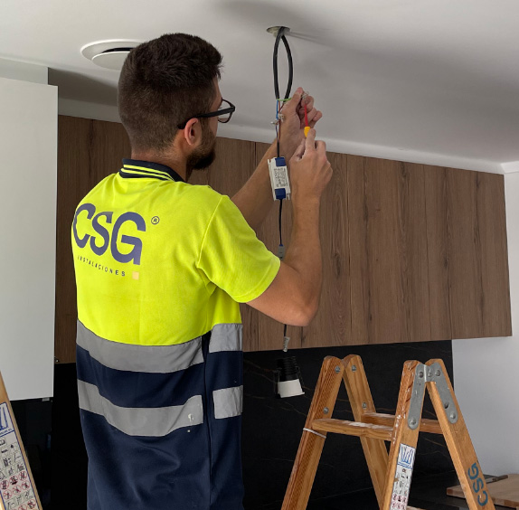 Electricista de CSG realizando una instalación en un techo
